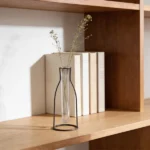 This decorative piece Outline Vase features a metal outline in the shape of a vase, offering a minimalist silhouette with a sculptural feel. Perfect for showcasing a single stem in its glass tube, it adds a subtle, artistic touch to your space. (glass tube vase included)
