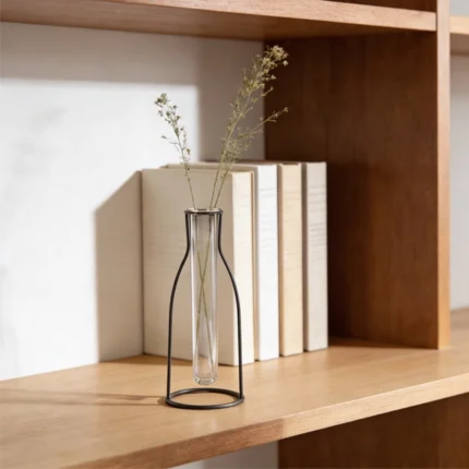 This decorative piece Outline Vase features a metal outline in the shape of a vase, offering a minimalist silhouette with a sculptural feel. Perfect for showcasing a single stem in its glass tube, it adds a subtle, artistic touch to your space. (glass tube vase included)