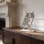Owl Decorative Object. A refined metal owl sculpture with a minimalist, architectural form. Compact yet expressive, it stands as a subtle statement piece on shelves, consoles, or desks, bringing character and quiet elegance to any interior. Ideal for contemporary, modern, or curated spaces.