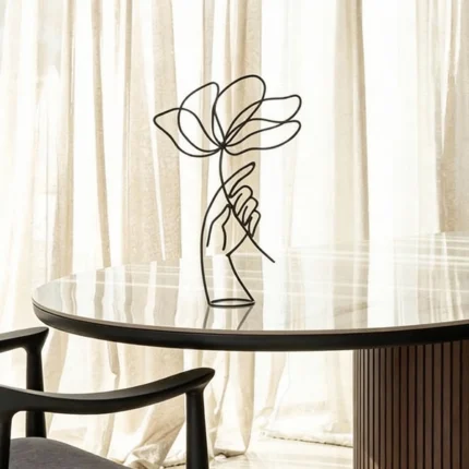 "Holding a flower" is a minimalist metal sculpture depicting a stylised hand delicately holding a flower—an evocative blend of modern art and subtle storytelling. Crafted from high-quality powder-coated metal, this elegant accent adds depth and emotion to any tabletop, shelf, or console. Compact yet expressive, it's available in several sophisticated finishes—Matte Black, Blue Sotara, Mountain Moss, and Rust—making it a refined choice for contemporary interiors and thoughtful gifting.